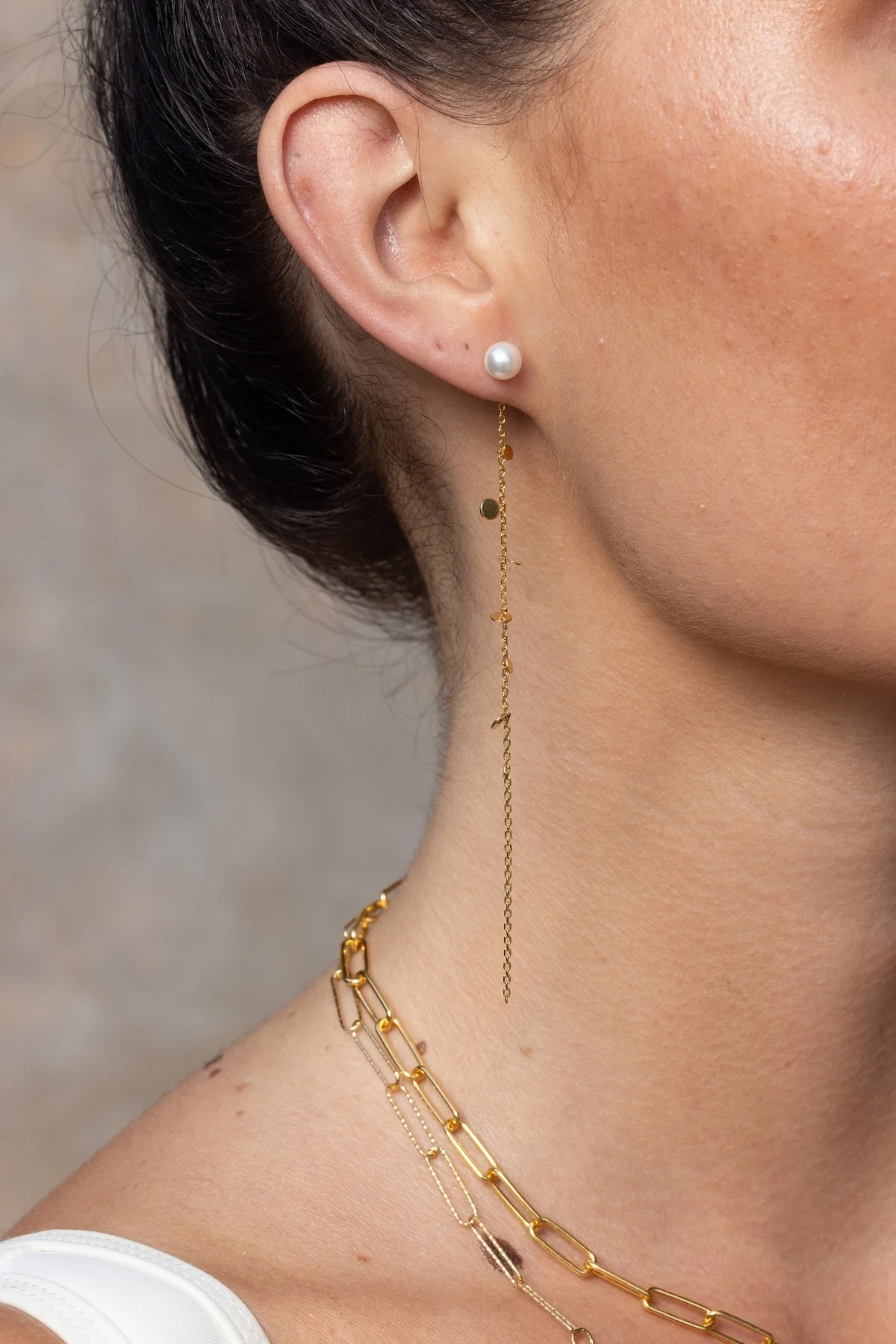 Boucles d'oreilles Sekoia dorées avec une délicate chaîne ornée de petits disques en métal doré et d'une perle, apportant une touche de sophistication et d'élégance.