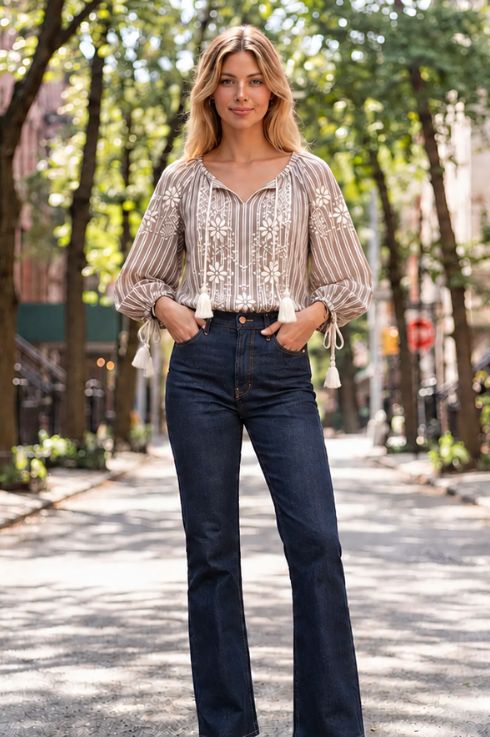 Blouse bohème bleu marine à imprimé floral doré et manches bouffantes, portée avec un jean et des bottes à franges devant un immeuble en brique à New York